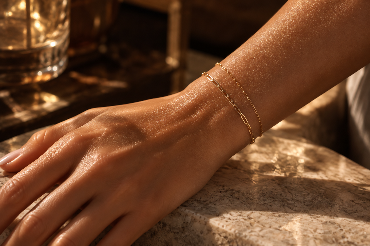 Gold permanent jewelry bracelets on a wrist — Lash & Brow Boutique